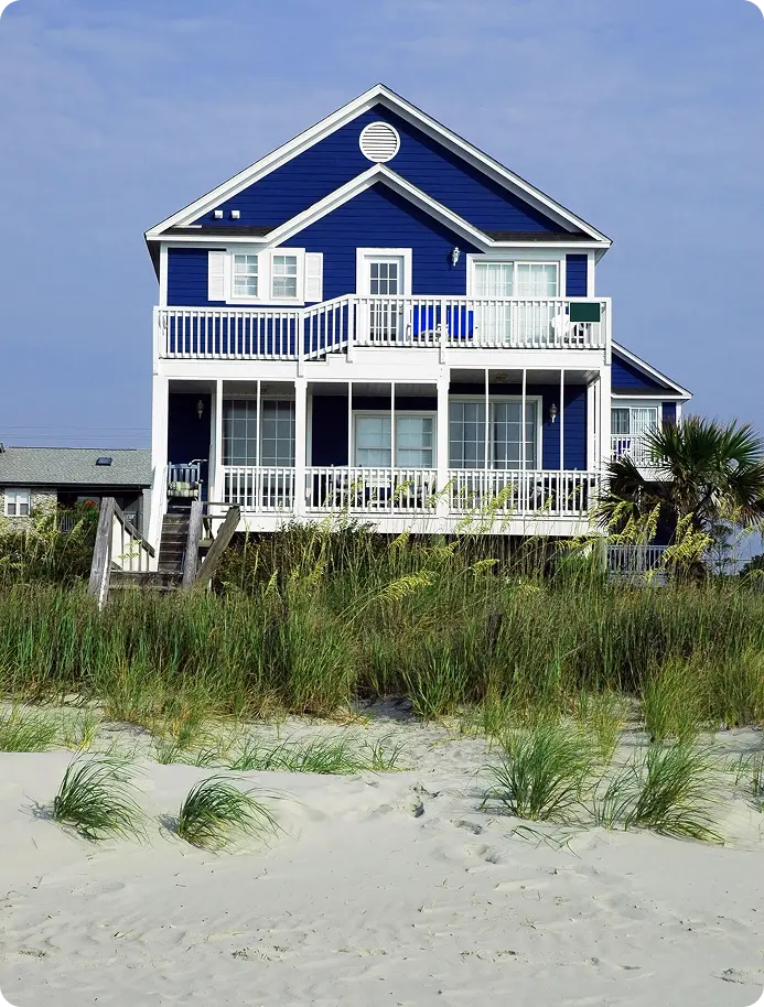 A blue house with a balcony overlooking the beach