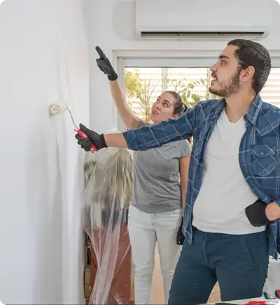 A man and woman engaged in painting a wall,
